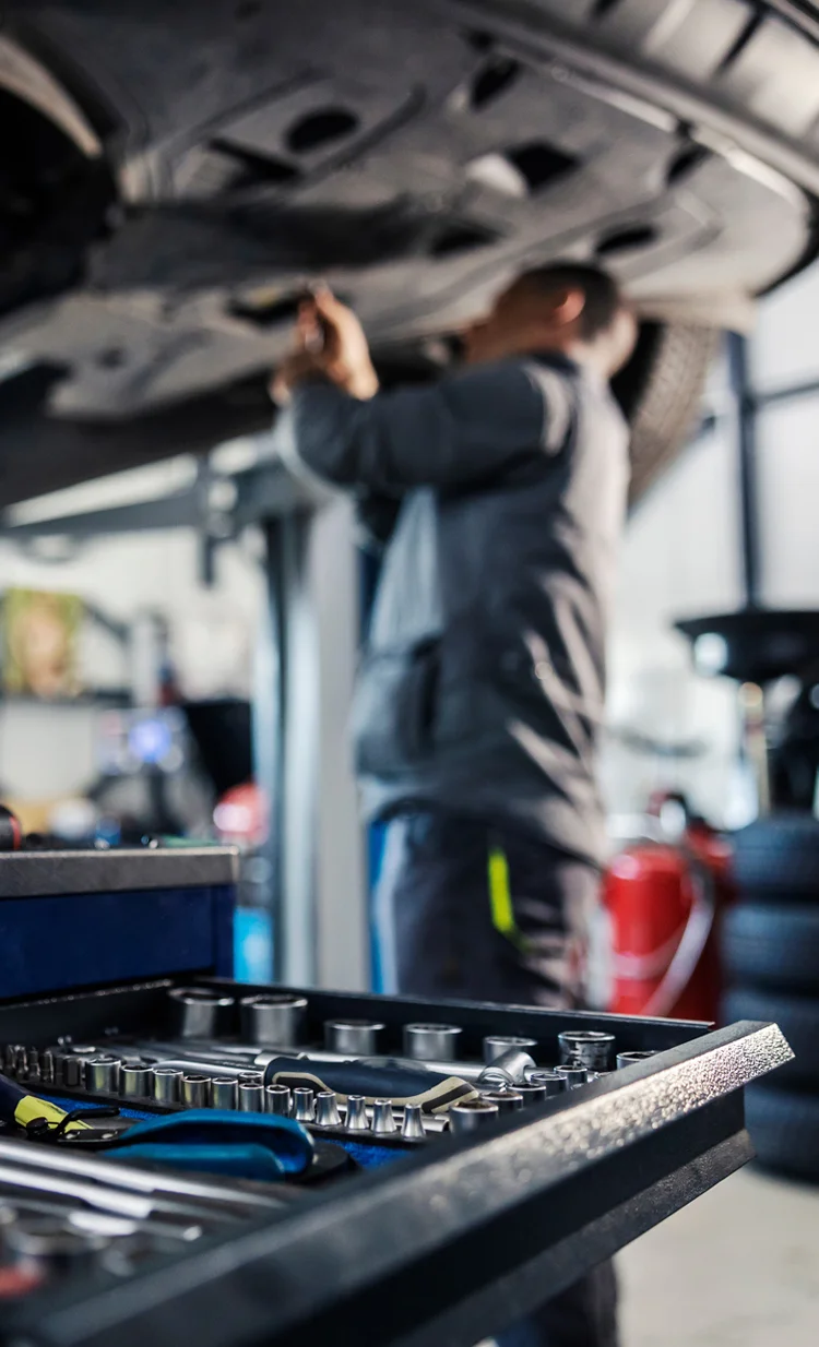 Technician working on a car in a busy independent workshop