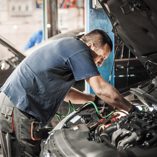 A technician servicing a car at a garage using Autopilot